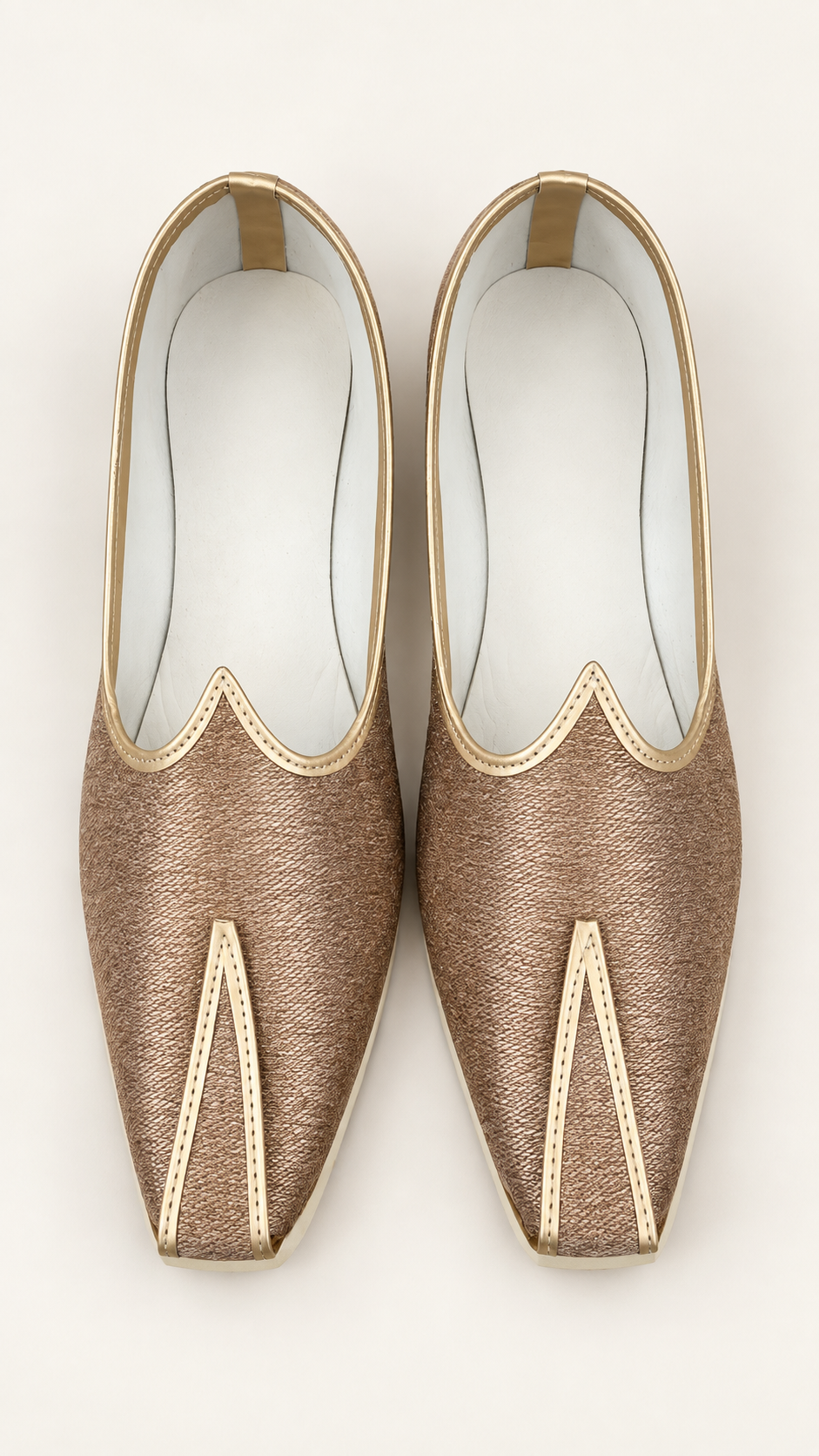 A pair of metallic gold slip-on shoes with pointed toes and decorative gold trim, shown from a top-down view on a light beige background.