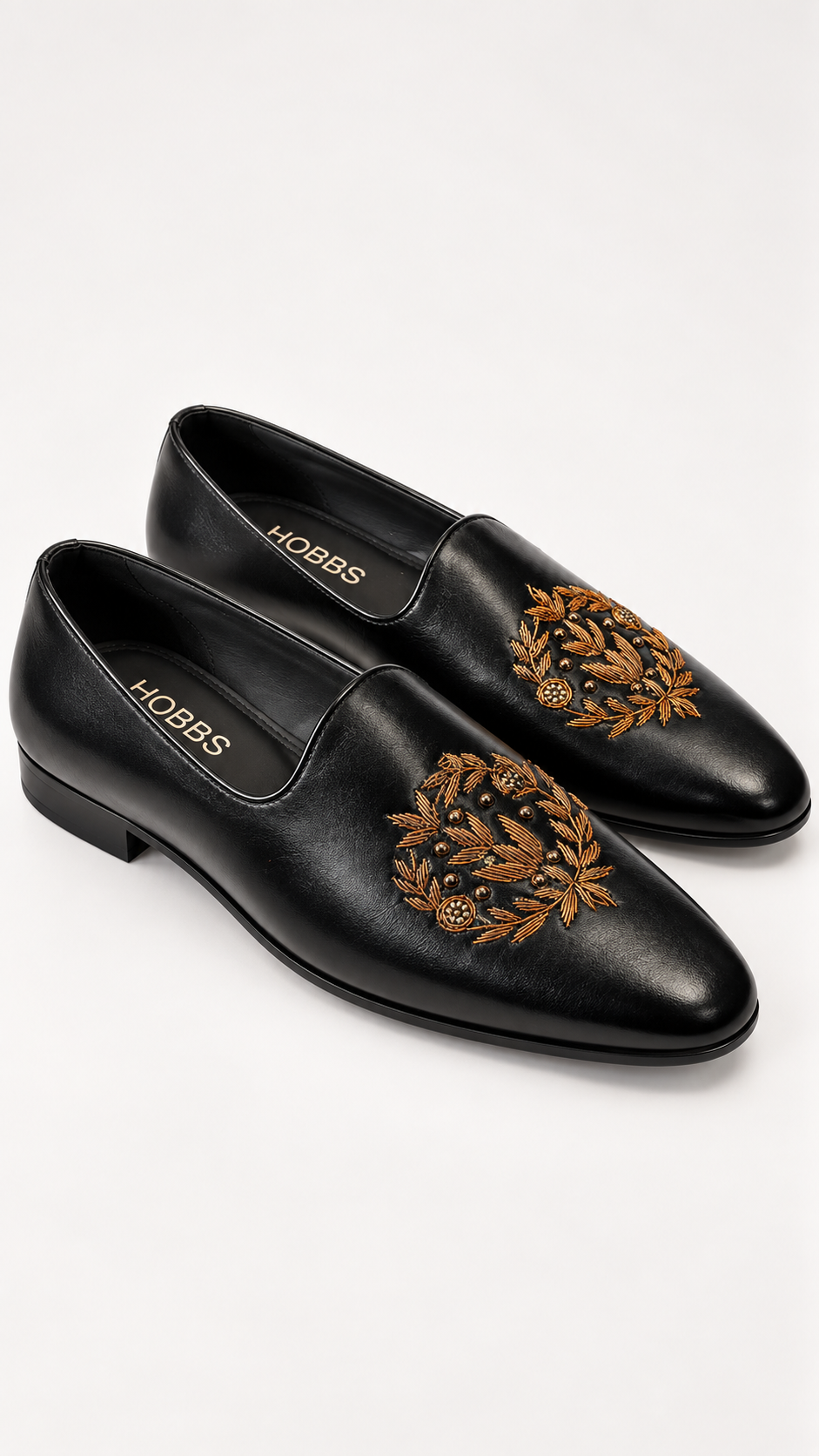 A pair of black leather pointed-toe loafers with ornate gold embroidered.