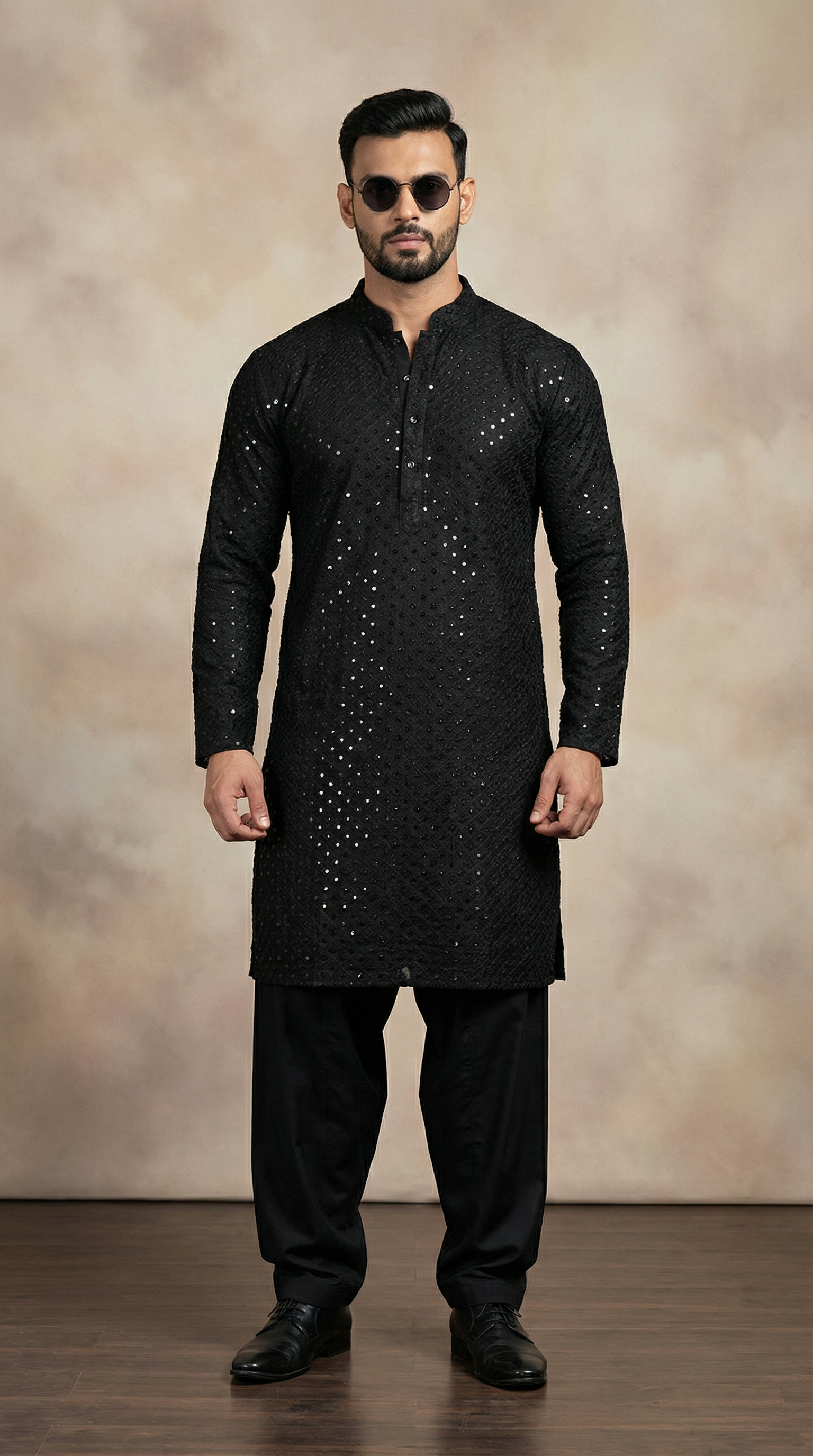 Man wearing a black kurta with intricate designs against a beige background