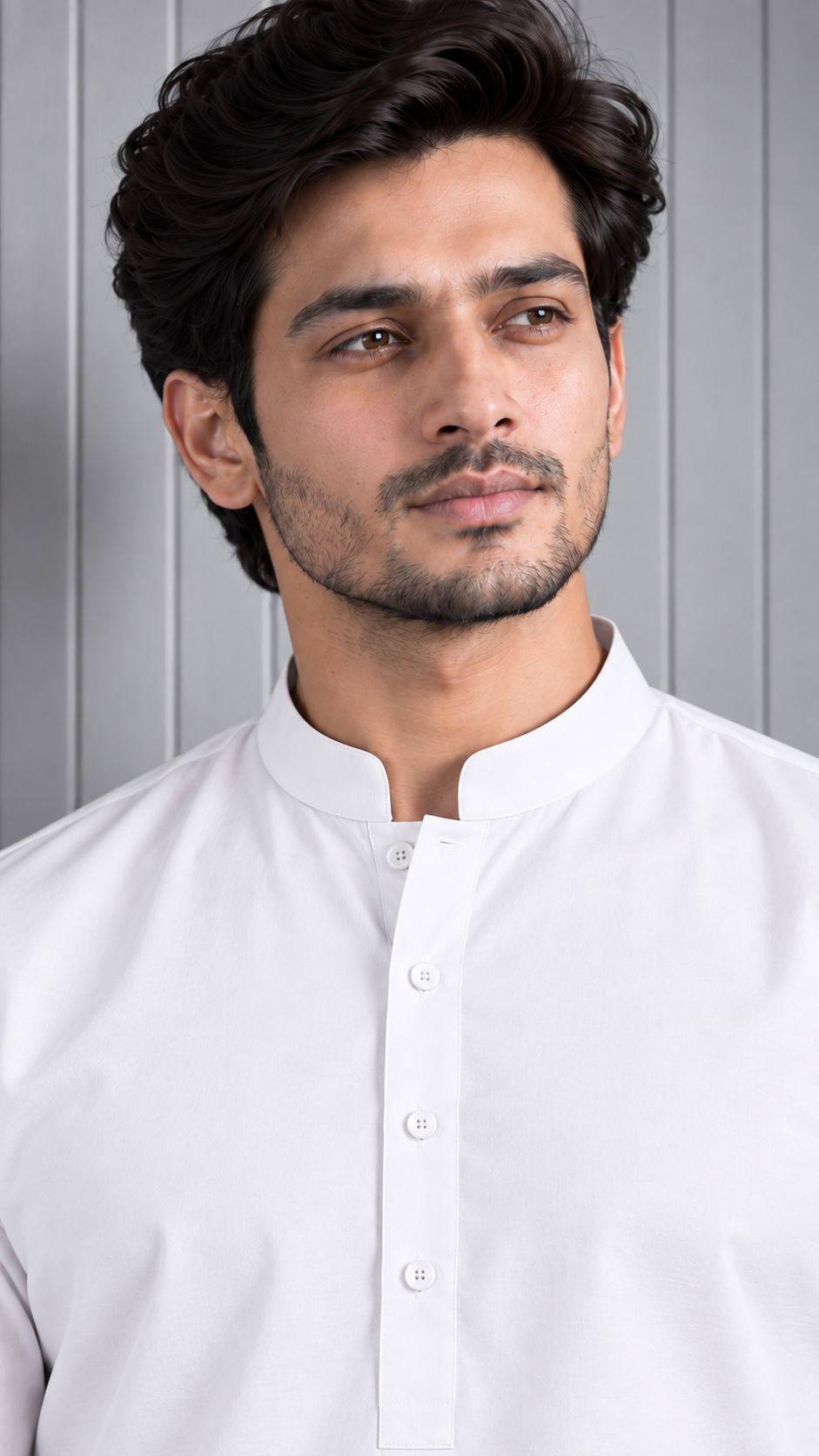 A man wearing a white long-sleeve kurta with a mandarin collar and button placket, shown from the chest up against a light gray paneled background.
