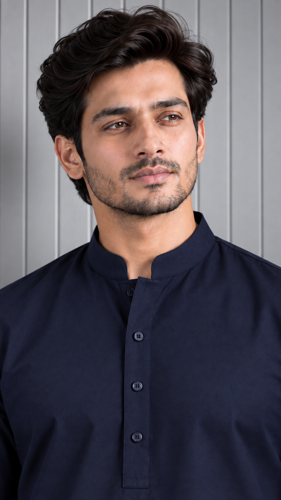 A man wearing a dark navy blue mandarin collar kurta, shown from the chest up against a gray paneled background.
