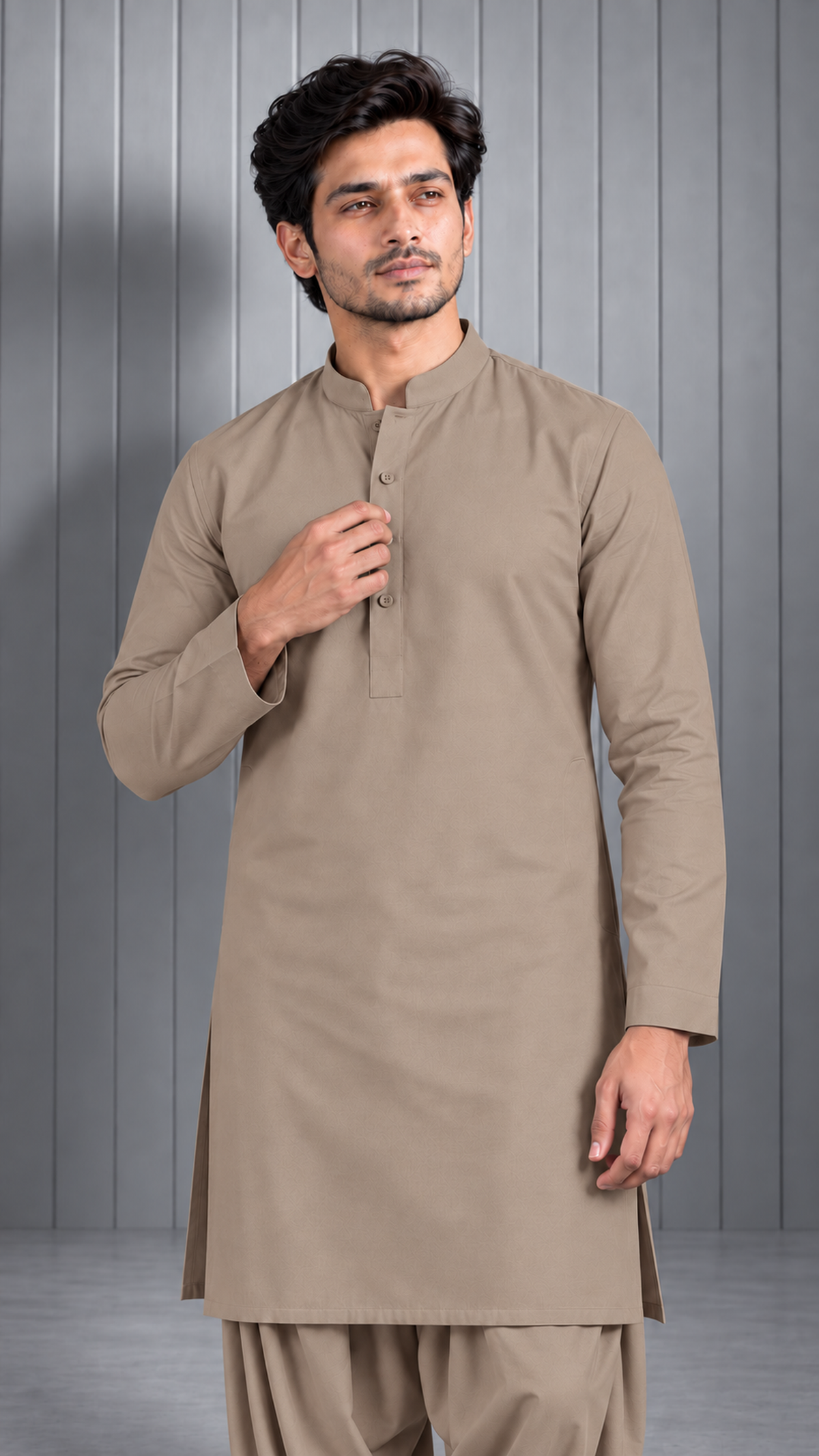 A man modeling a light brown long-sleeve kurta with a band collar and three-quarter button placket, paired with matching trousers, set against a gray paneled studio background.