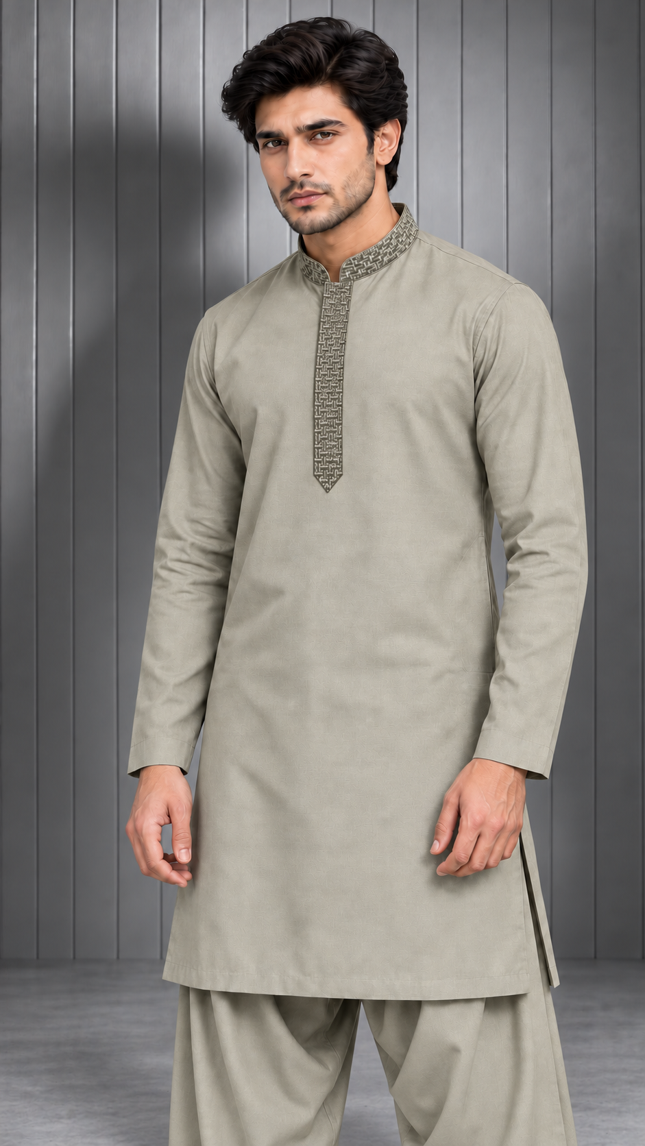 A man modeling a light beige long-sleeve kurta with a textured patterned placket and matching beige trousers, standing against a gray paneled studio background.