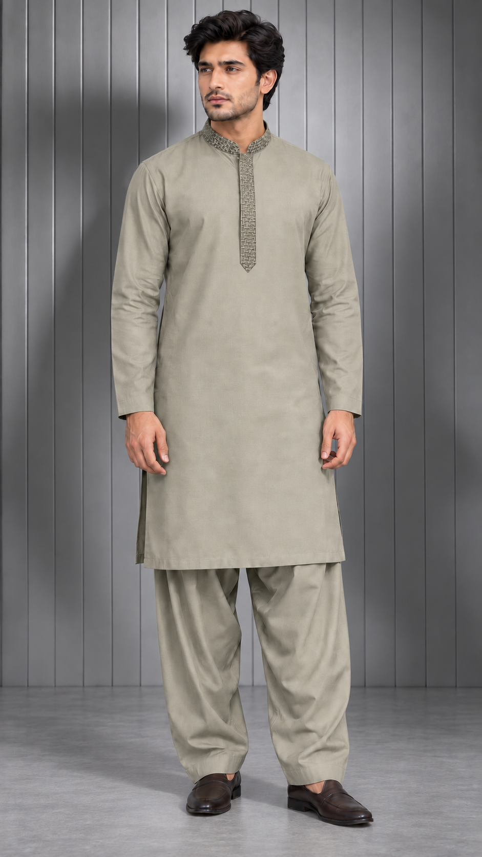 A man modeling a light beige/khaki traditional Indian kurta and pant set against a gray paneled studio background.