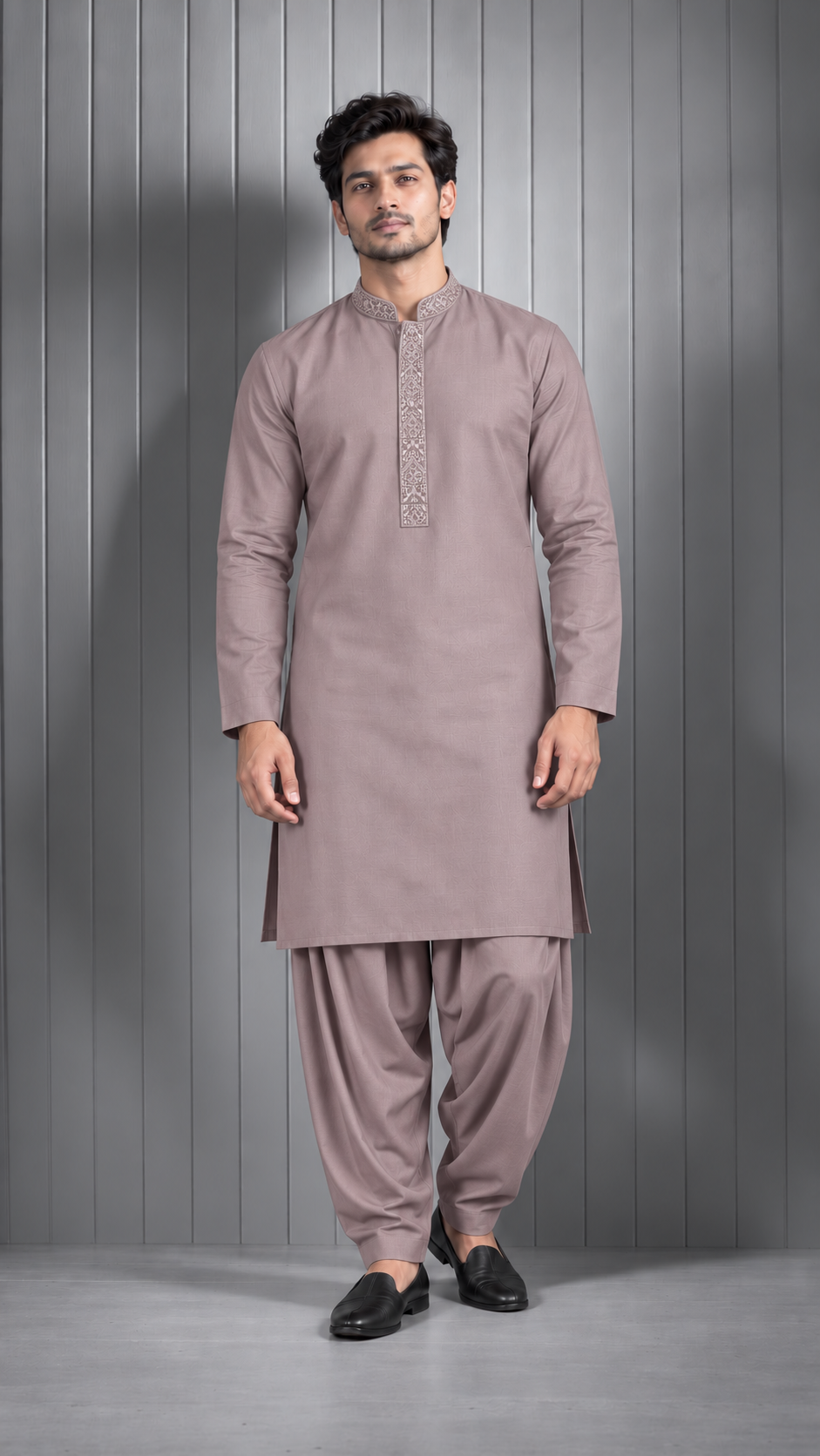A man modeling a traditional outfit consisting of a long-sleeve kurta and matching pants in a dusty mauve color, standing against a gray paneled studio background.