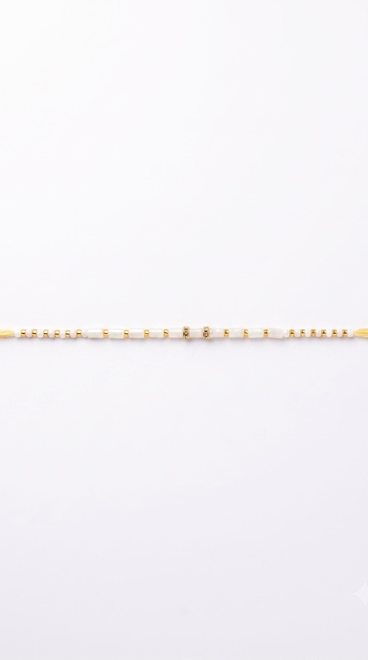 Minimal white beaded rakhi bracelet with gold-tone spacer beads worn on a man's wrist – Diya Online