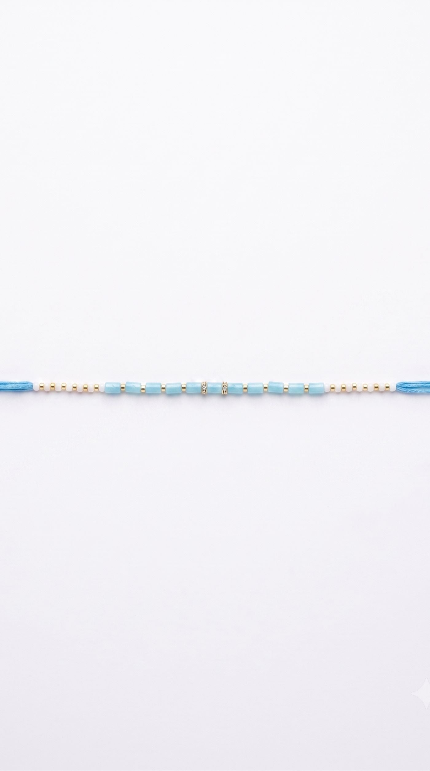 Minimal blue and white beaded rakhi bracelet with gold-tone spacer beads worn on a man's wrist – Diya Online